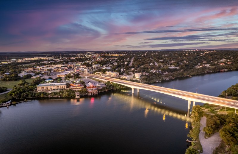Downtown Marble Falls at sunset with the lit bridge over the water